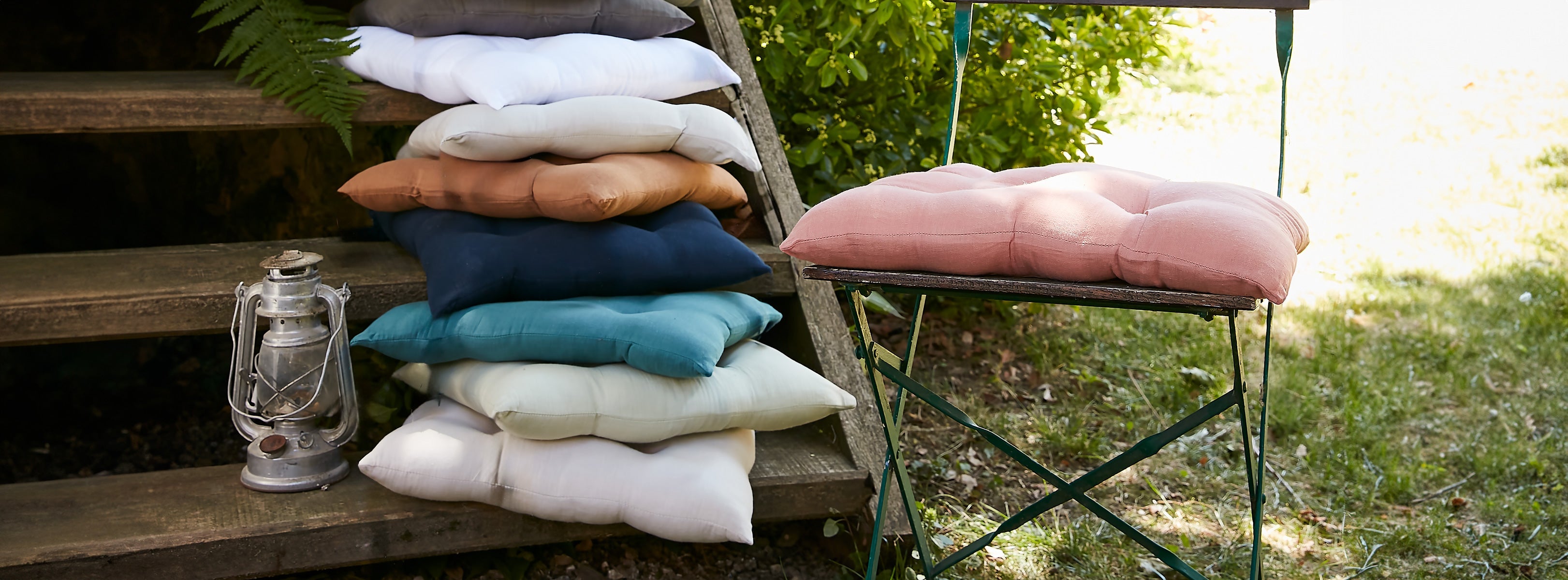 Assortiment de galettes de chaise colorées en gaze de coton empilées sur un escalier de jardin en bois