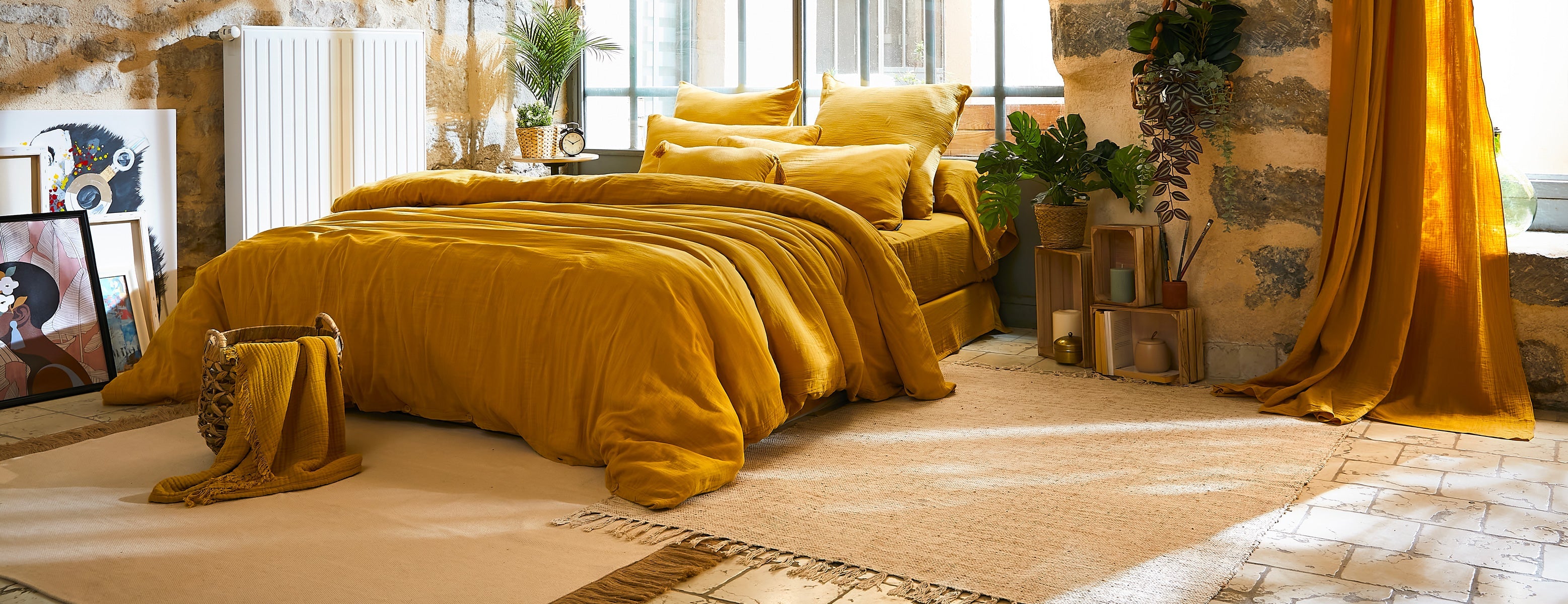 Chambre lumineuse avec parure de lit en gaze de coton jaune safran, plaid assorti et rideaux jaunes
